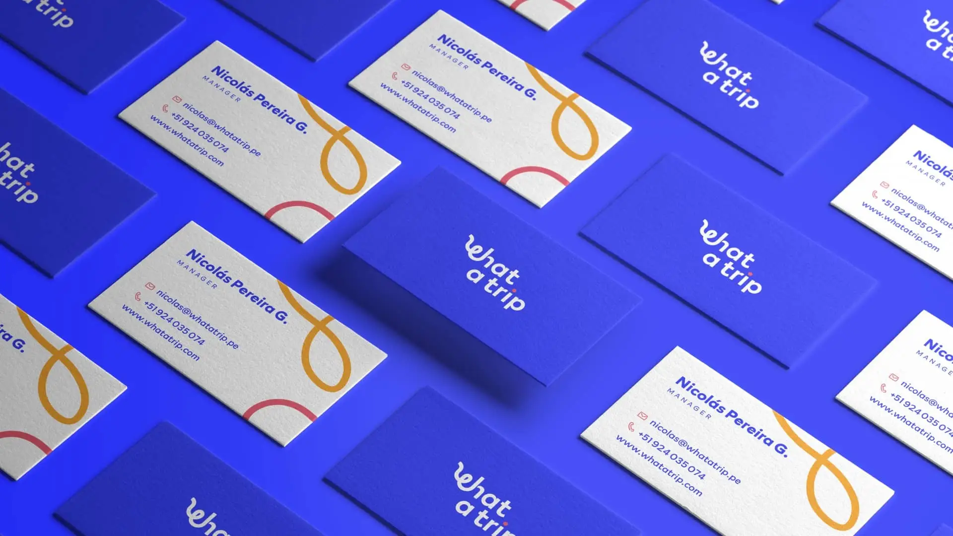 Mockup de tarjetas de presentación de la marca 'What a Trip' organizadas en diagonal sobre fondo azul, alternando entre el reverso azul con el logotipo blanco y el anverso blanco con trazos curvos amarillos y rojizos junto a información de contacto