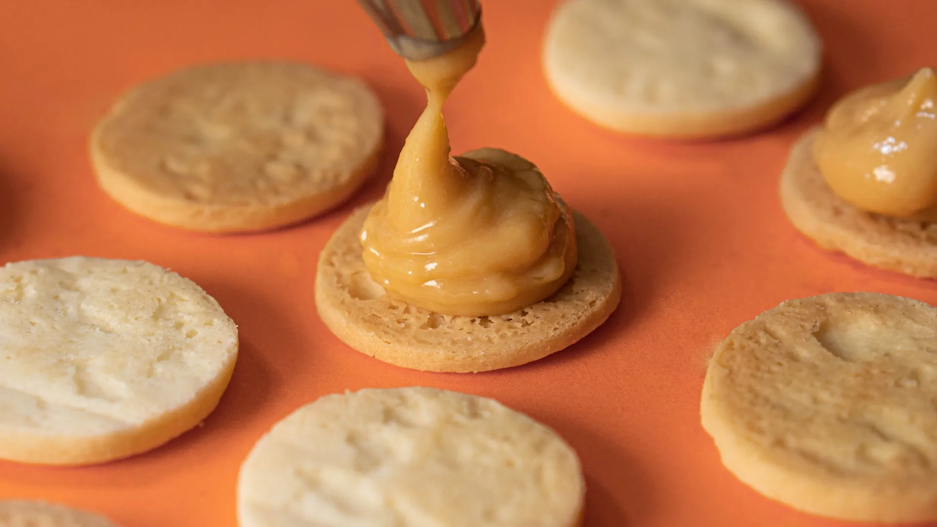 Proceso de relleno de galletas con crema dulce aplicado sobre tapas de masa horneada