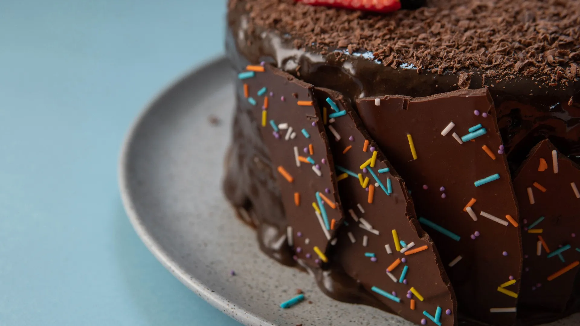 Pastel de chocolate decorado con cobertura brillante y grageas de colores sobre plato