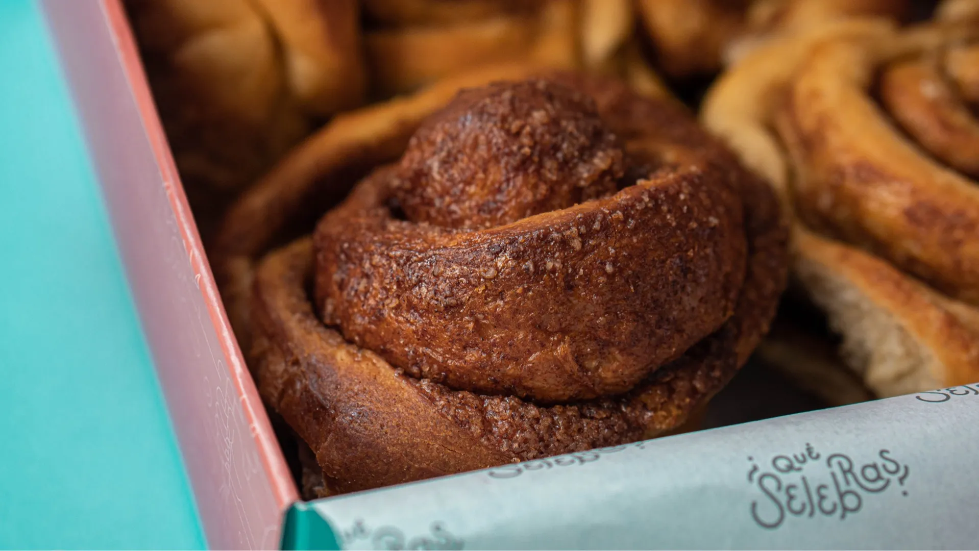 Primer plano de rollo de canela horneado dentro de caja con papel decorativo