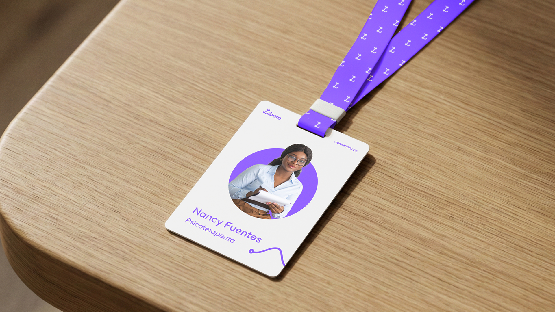 Credencial corporativa con cinta morada colocada sobre superficie de madera