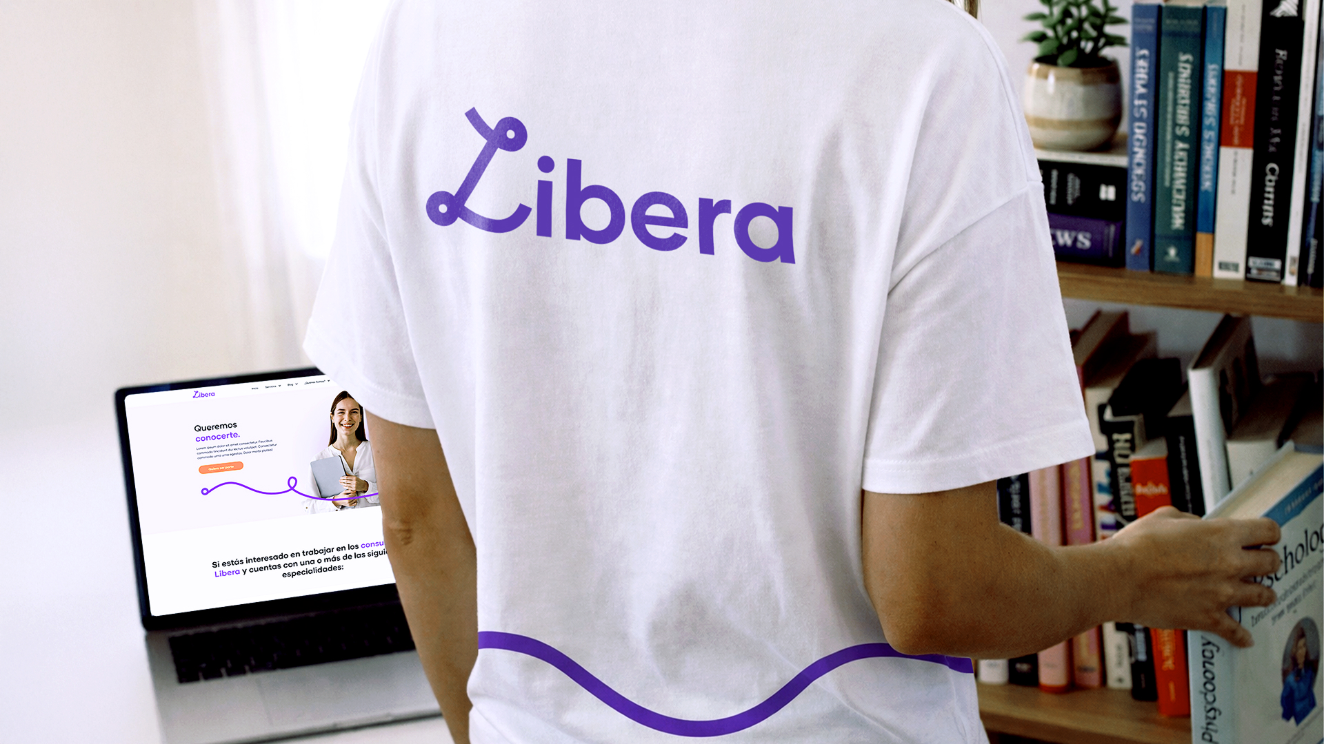 Camiseta blanca con logotipo de marca en entorno interior con laptop abierta