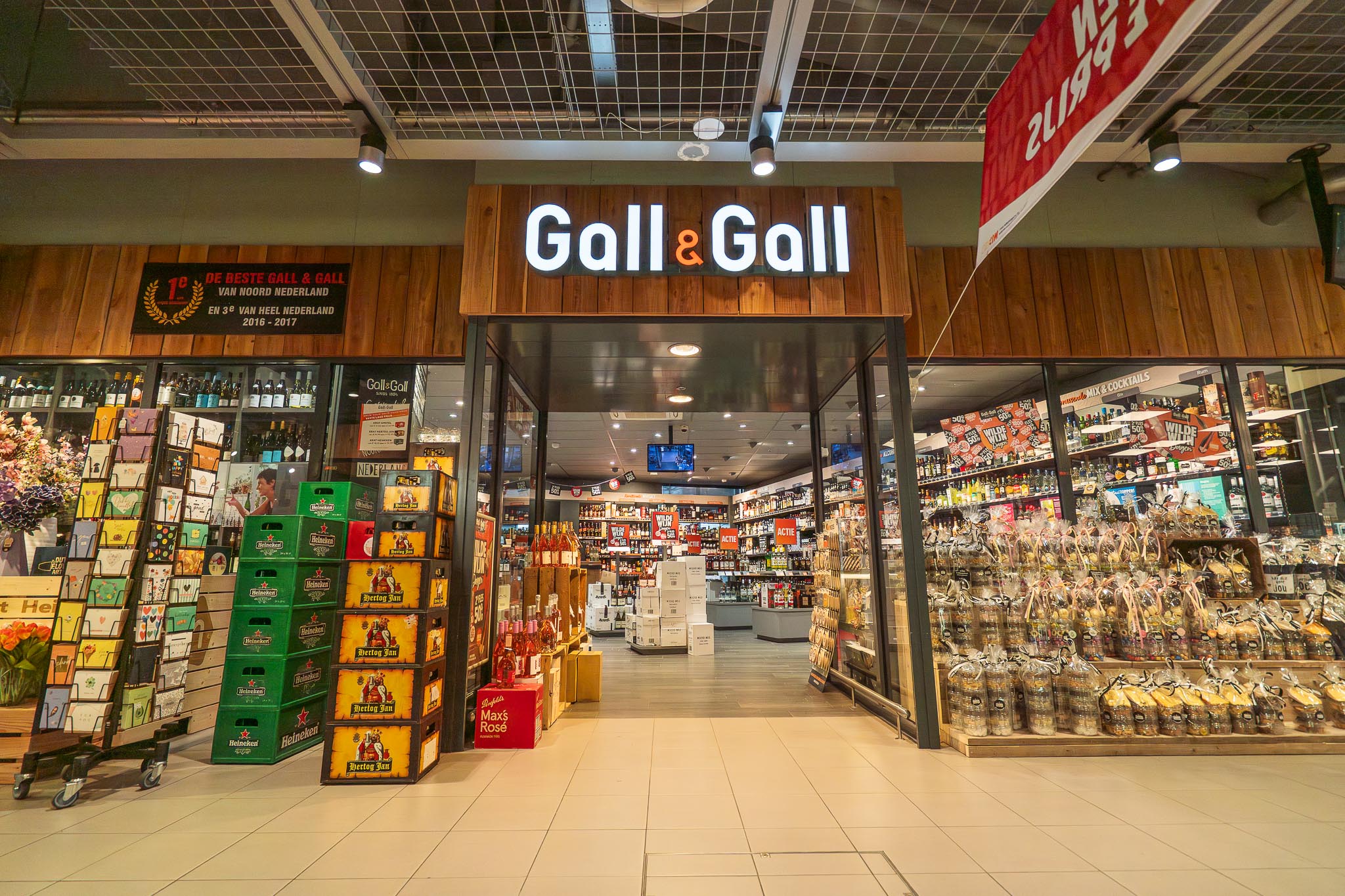 Ingang van een Gall & Gall winkel met rekken vol drankflessen en geschenkverpakkingen.