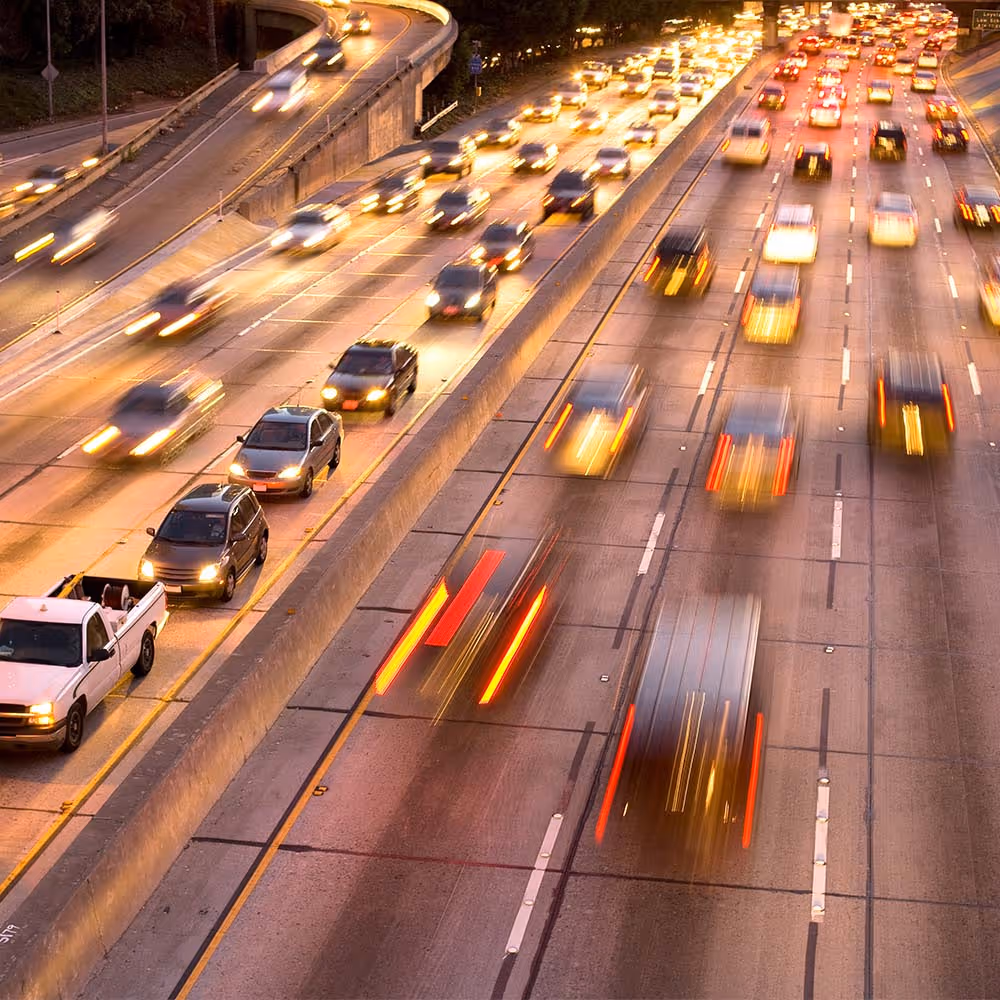 Blurred view of heavy traffic on a multi-lane highway with cars and buses in motion.