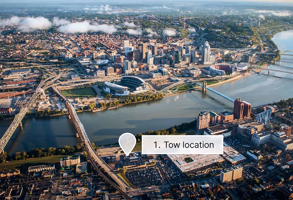 Aerial view of a city with rivers, bridges, and a marker indicating a tow location near the water.