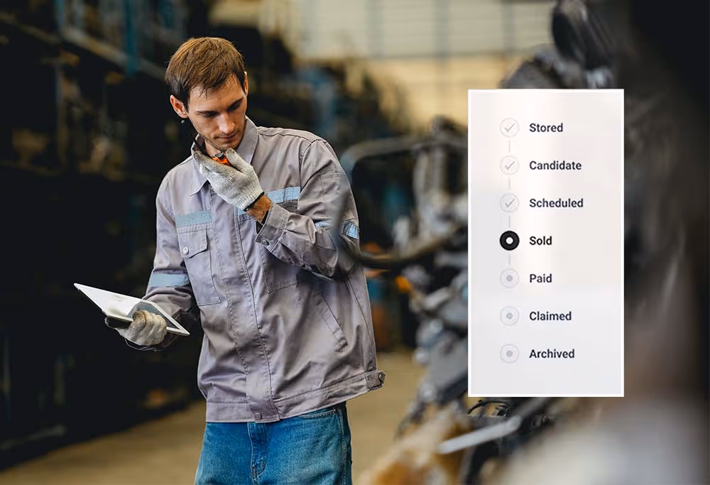 Man in work clothes holding a tablet with checklist showing 'Sold' status highlighted in warehouse.