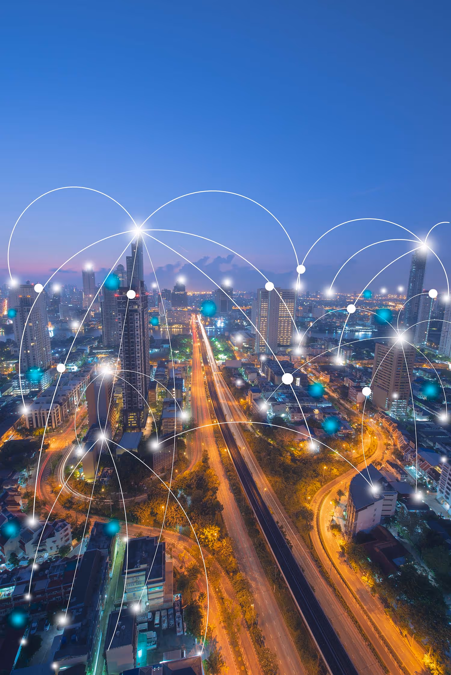 A smart city at dusk with illuminated roads and digital network connection overlays among buildings.