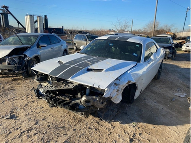 Unclaimed white 2016 Dodge Challenger with a missing fender parked in an impound lot
