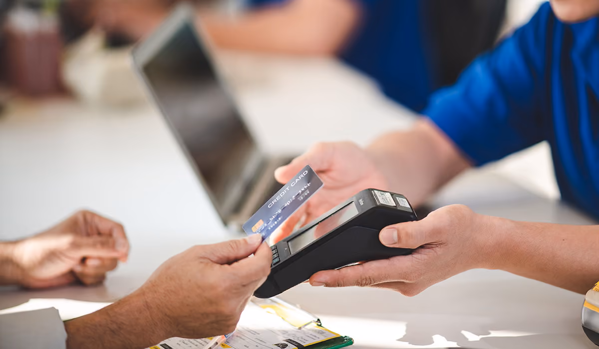 Credit card being tapped to payment terminal at a counter top