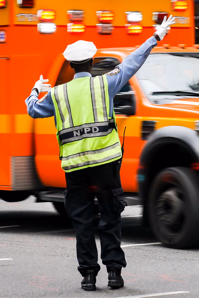Cop in high visibility vest directing ambulance in New York City