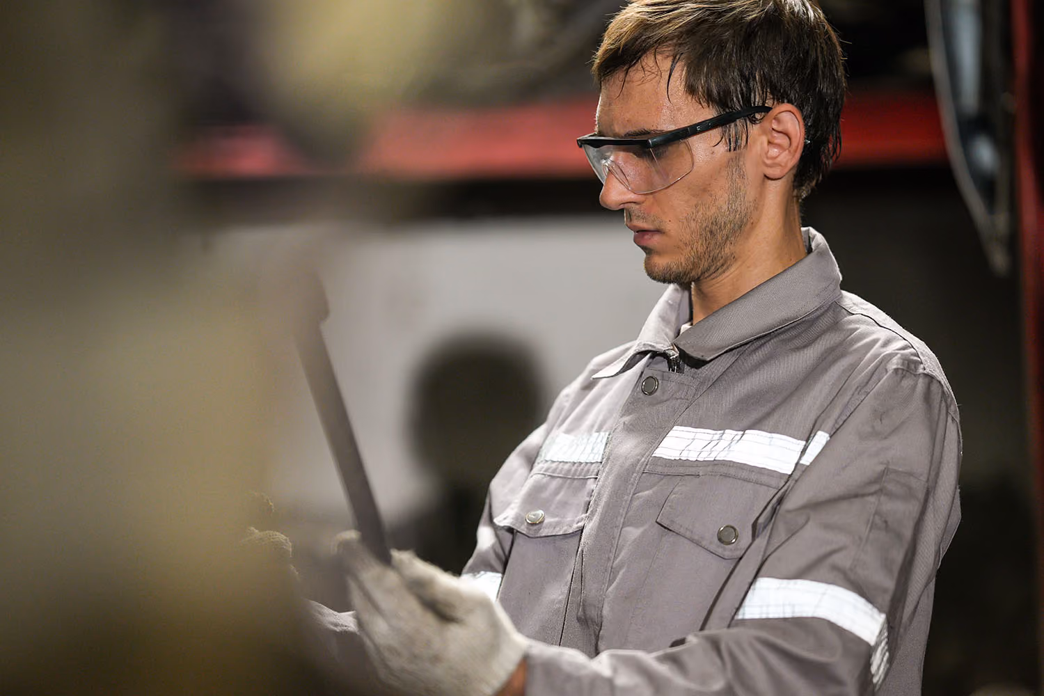 Man in googles and work clothes looking at a clipboard