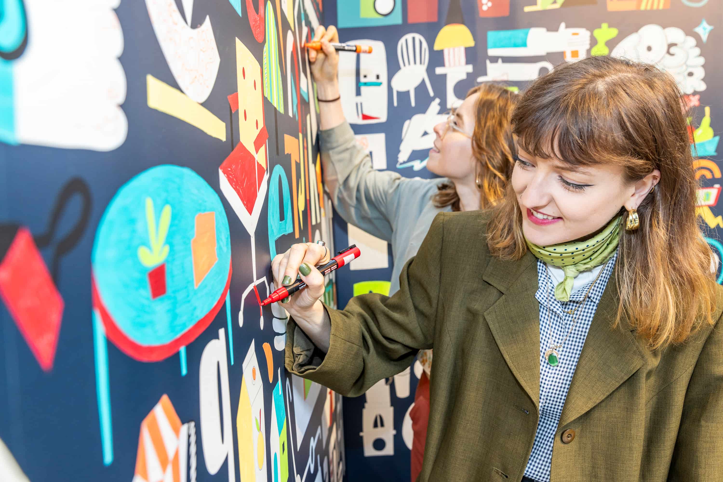 An image from a Select First event showing to women taking part in a giant community-built paint by numbers mural.