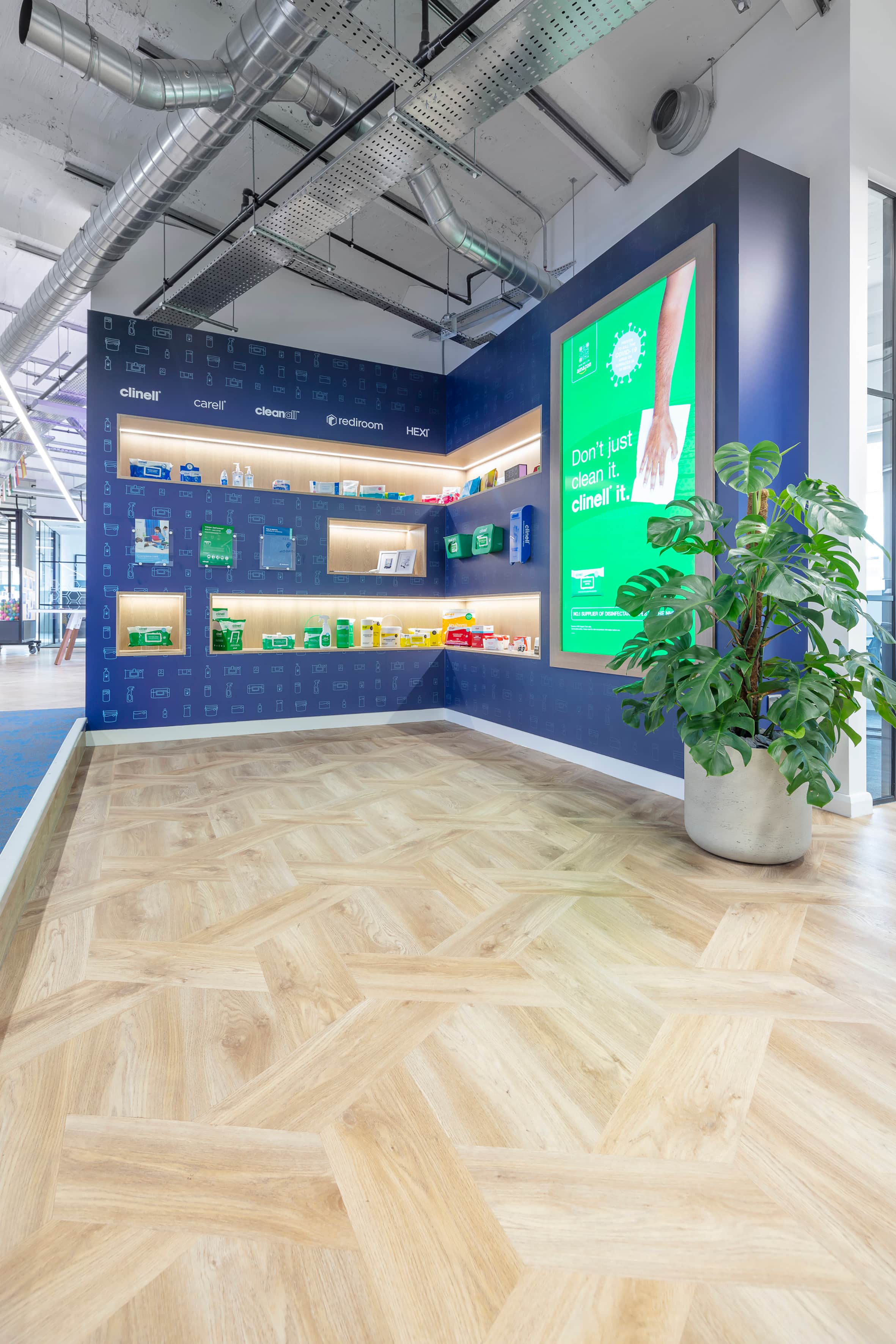 A case study picture looking at new flooring in a commercial setting with a promotional display and plant in the frame.