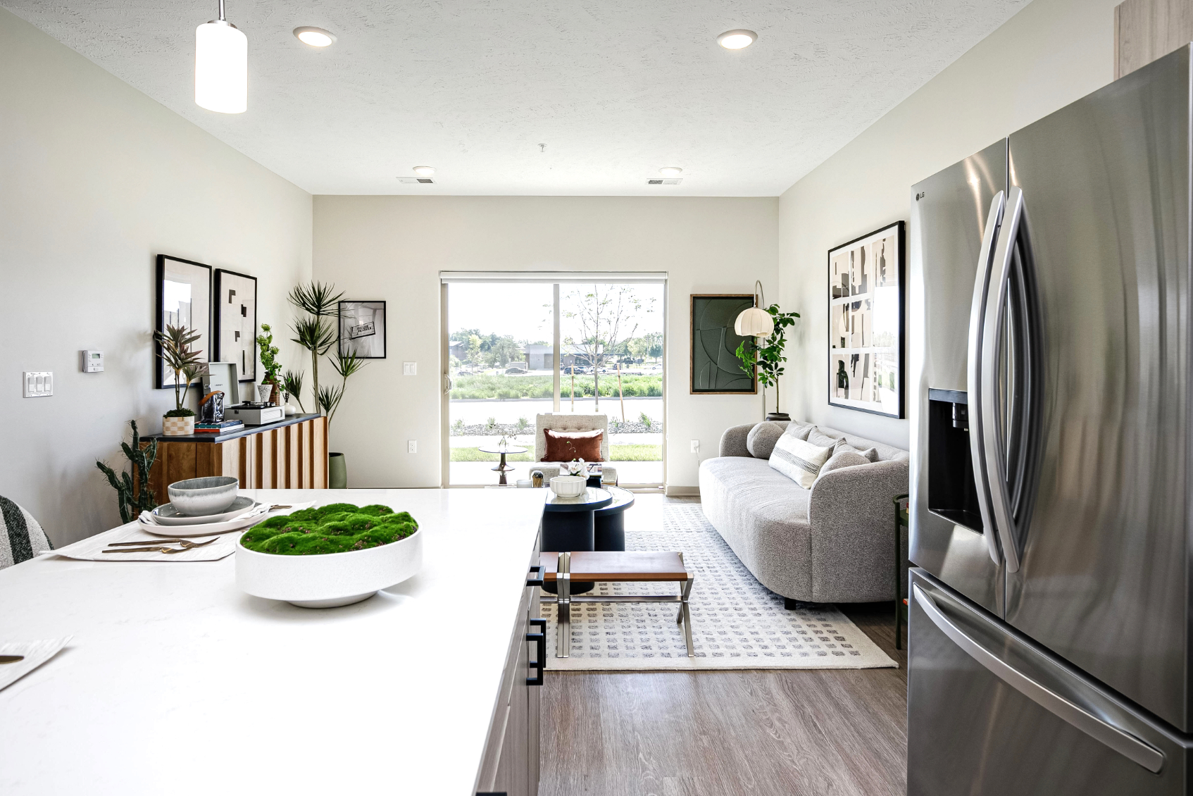 Kitchen with island, stainless steel fridge and view into living area with sofa