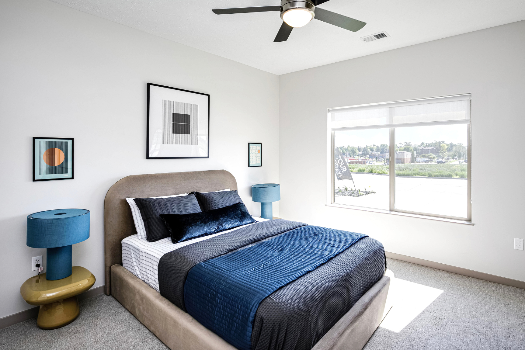 Wide view of contemporary bedroom with bed, bedside table, lamp, and large window