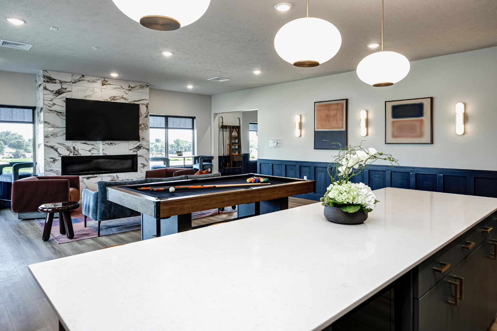 Clubhouse game area with billiards table, tv, and fireplace view from kitchen area