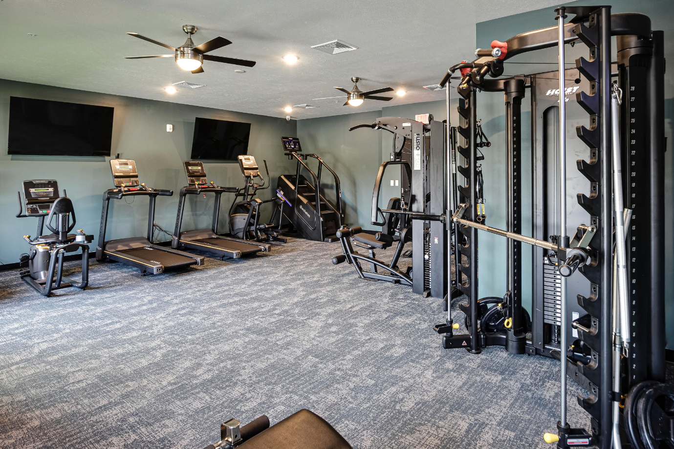 Clubhouse gym with fitness equipment featuring treamills