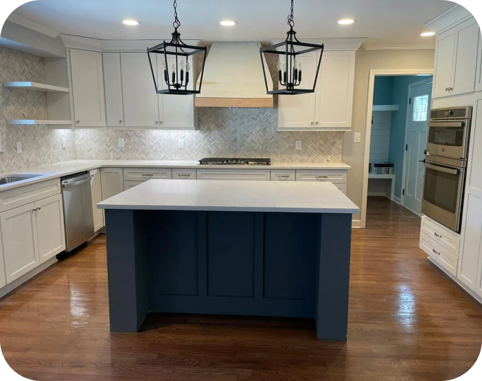 Modern kitchen with white cabinets, herringbone tile backsplash, stainless steel appliances, dark blue island, and hardwood floor.