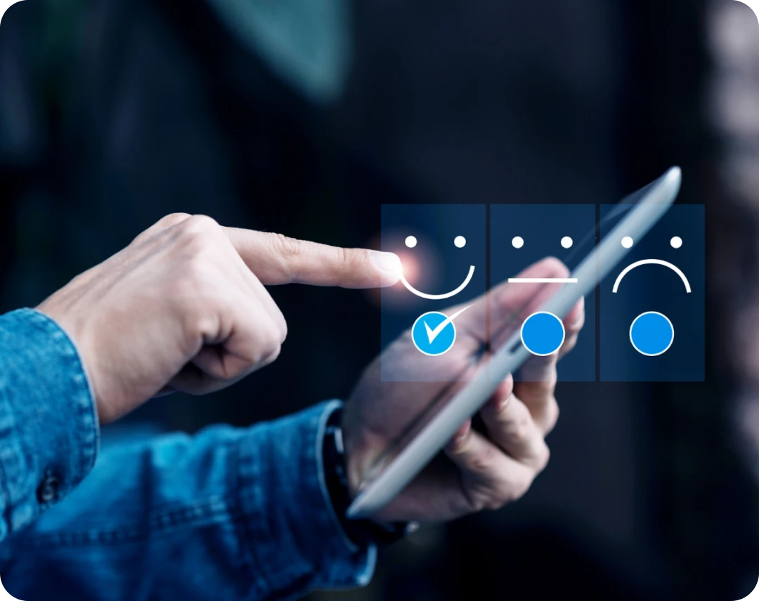 Person using a tablet, selecting a happy face icon on a digital feedback rating scale.