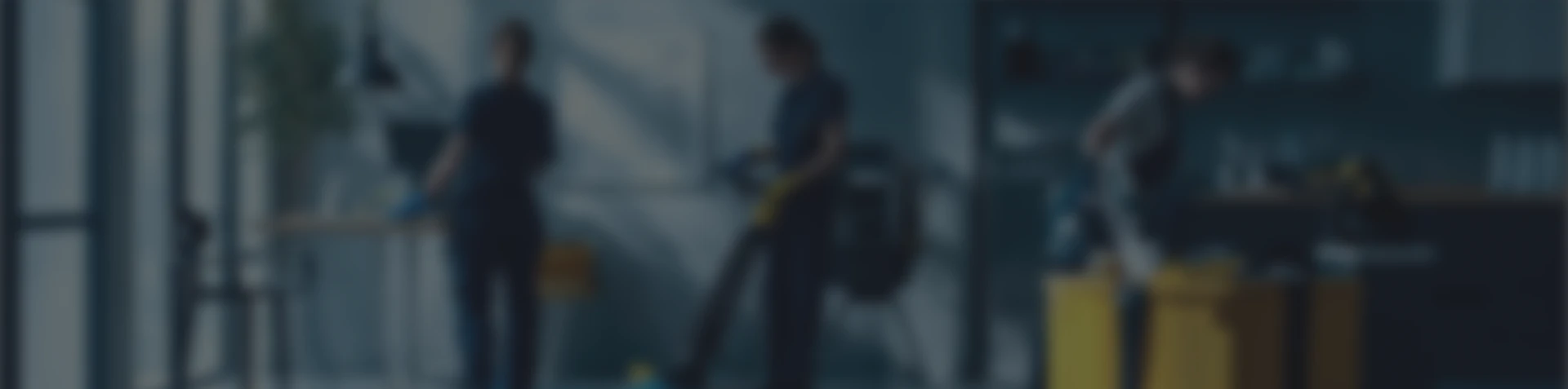 Three people cleaning a modern office space using vacuum and cleaning supplies.