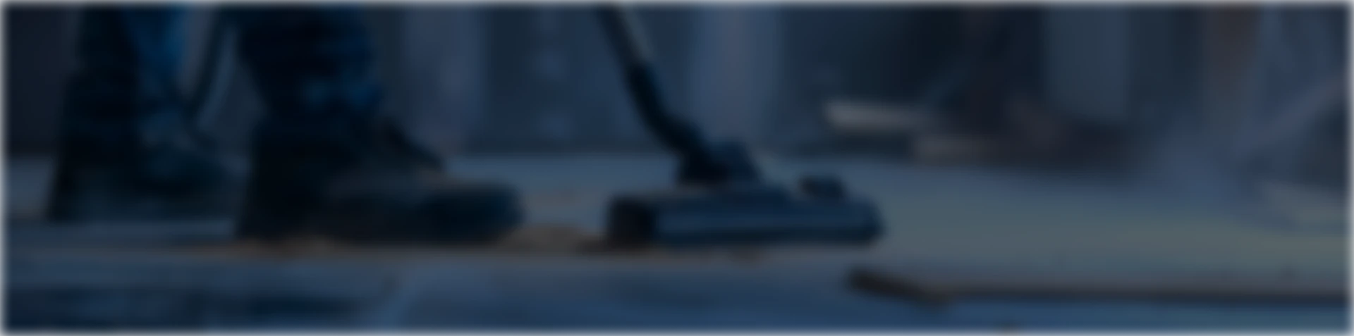 Person vacuuming dust from a floor using a vacuum cleaner.