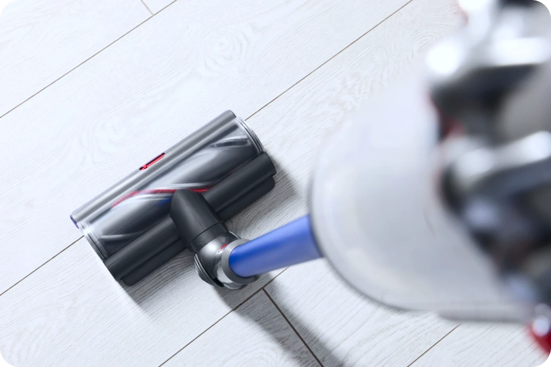 Close-up of a cordless vacuum cleaner head on a light wood floor.