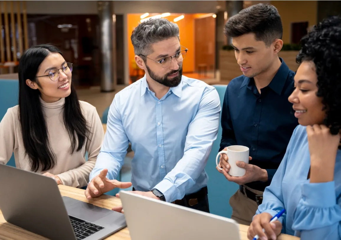 Three individuals collaborating around a laptop, discussing computer vision solutions for business transformation.