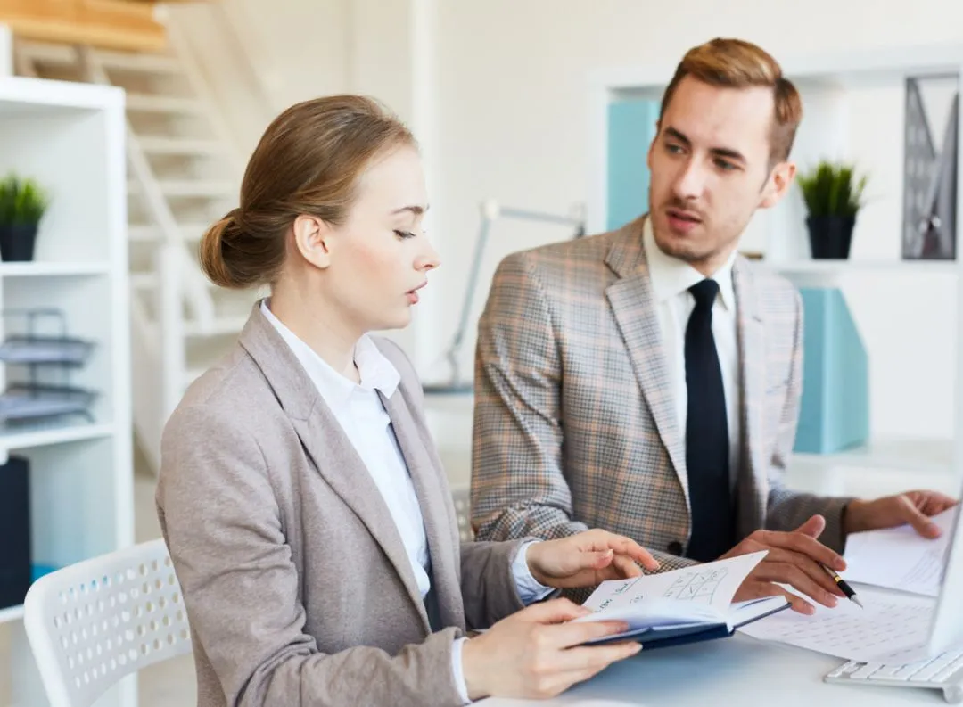 Three individuals collaborating around a laptop, discussing computer vision solutions for business transformation.