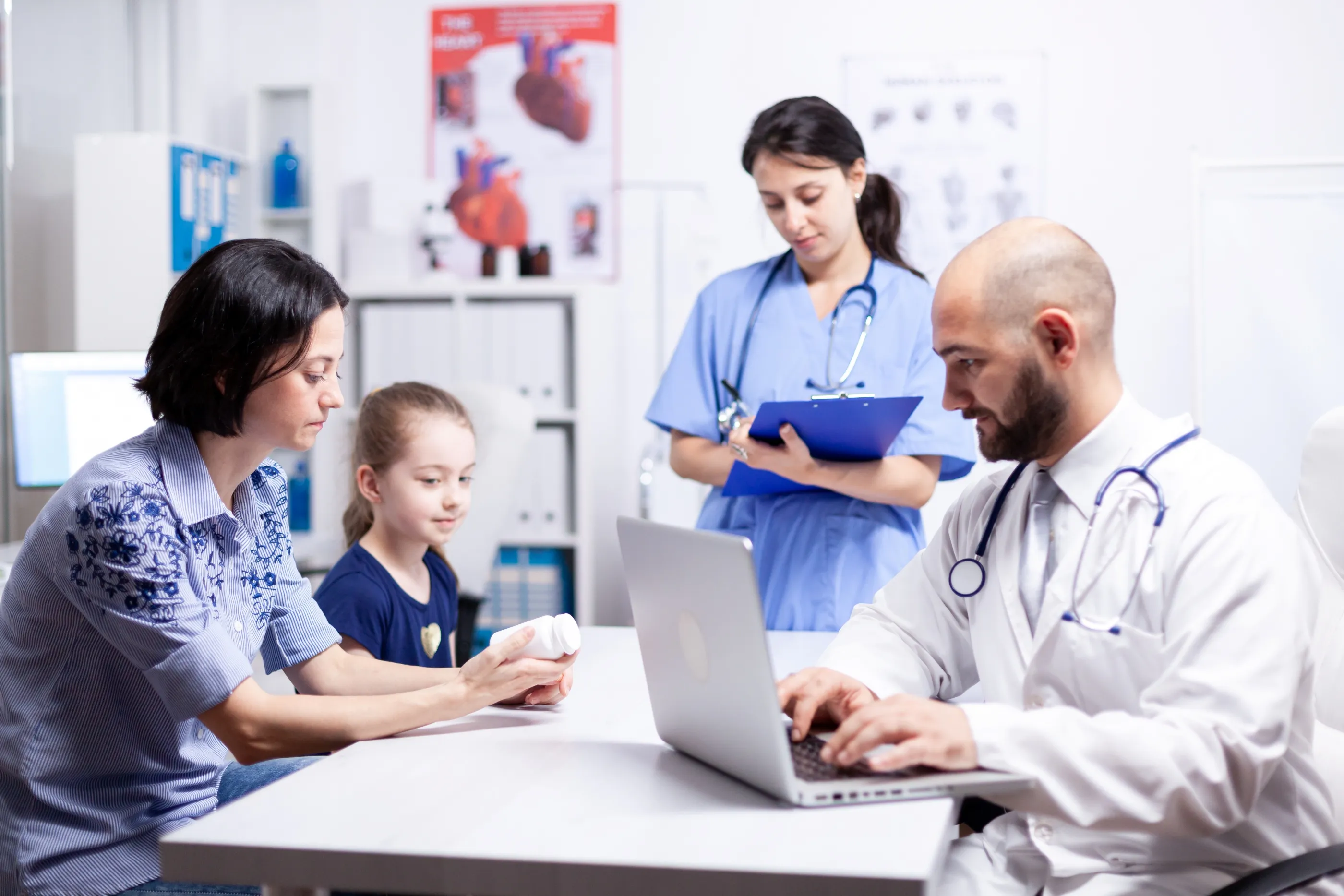 A family consults with a doctor at a table, engaging with a laptop for healthcare discussions and solutions.
