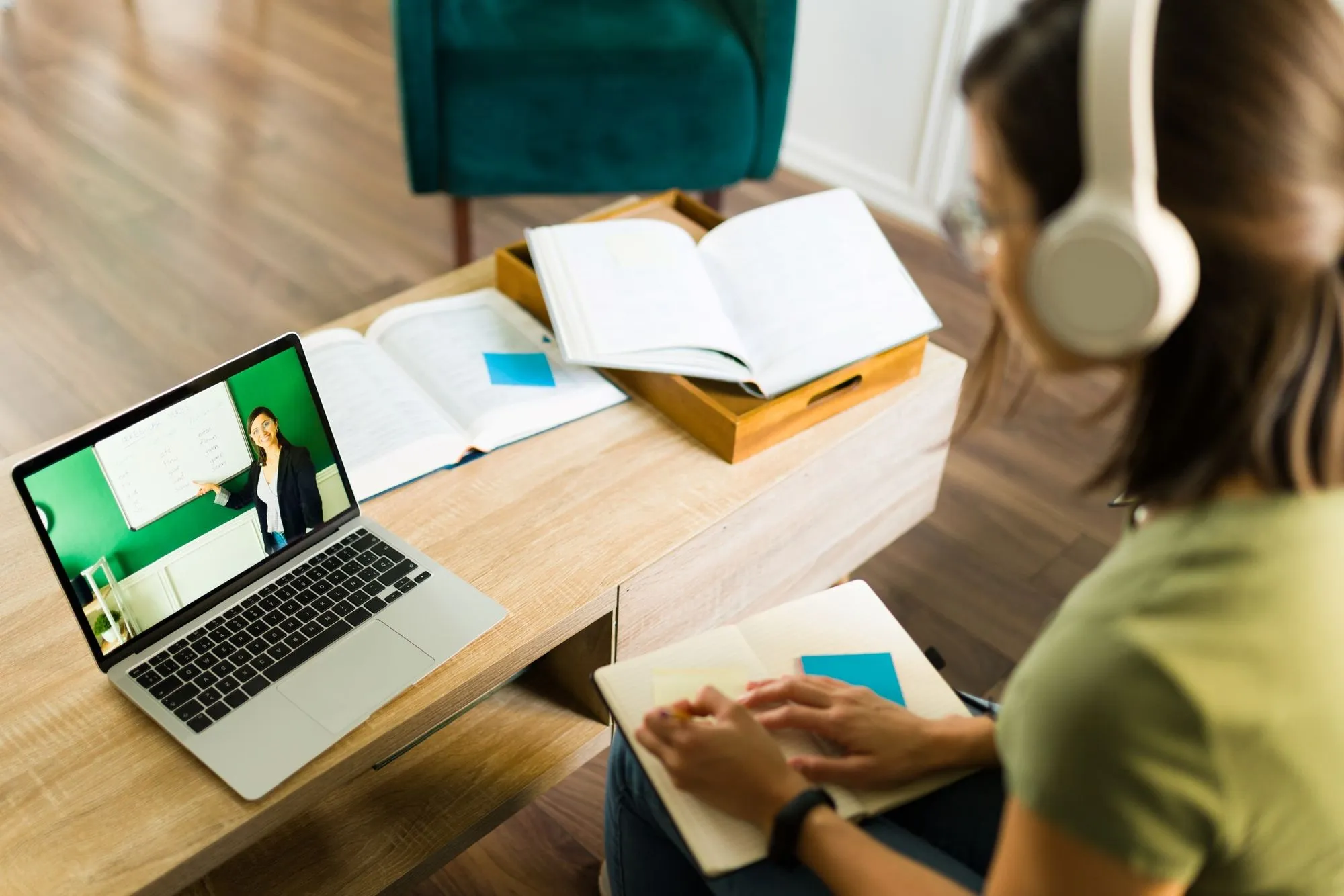 A woman wearing headphones sits at a desk, focused on her laptop, working on educational platform design and integration.
