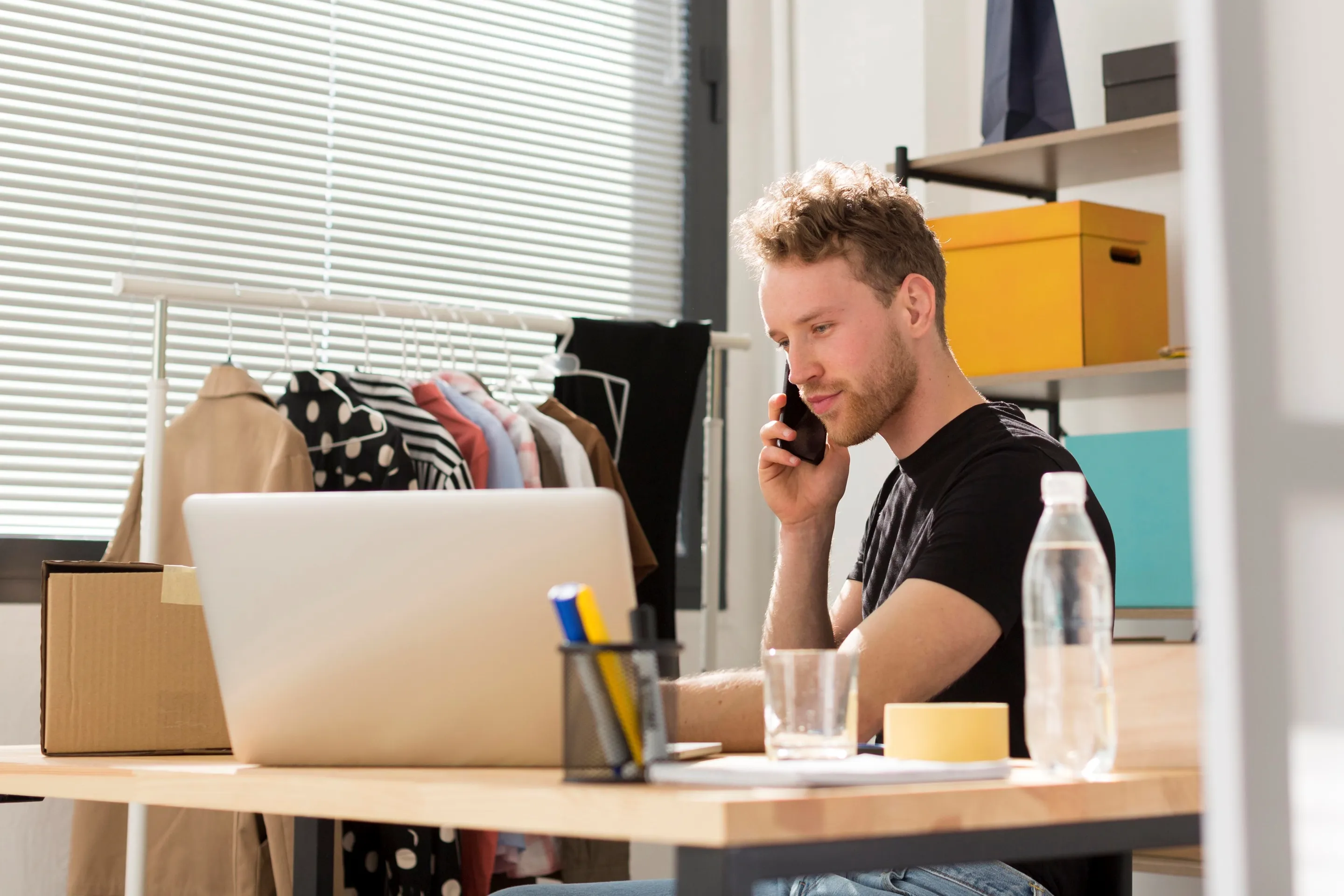 A man at a desk using a laptop while talking on the phone, focused on revitalizing salesforce commerce cloud sales strategies.