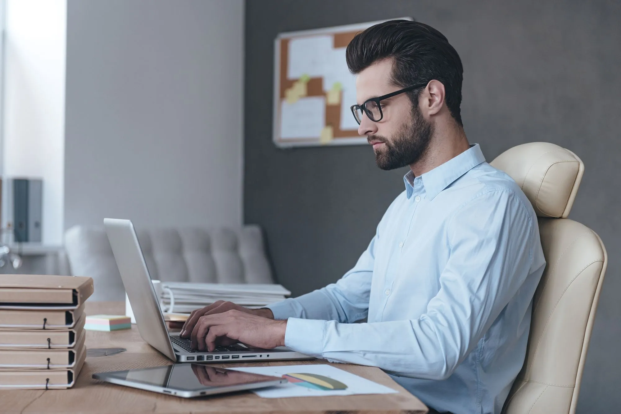 A man wearing glasses sits at a desk with a laptop, focused on scaling a Healthtech platform with CTO leadership.