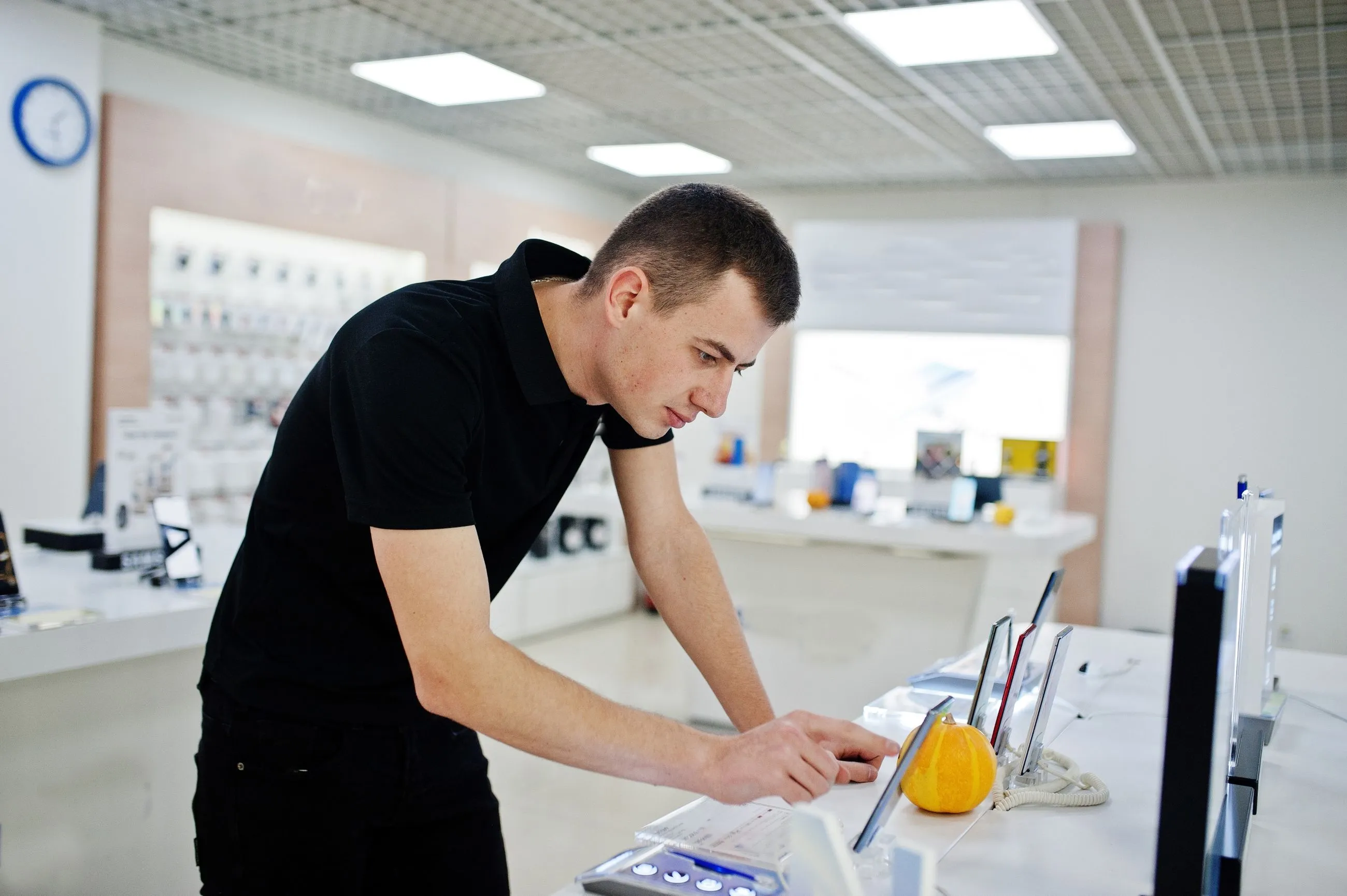 A man using a laptop in a retail store, focused on optimizing field service management with ServiceNow FSM tools.