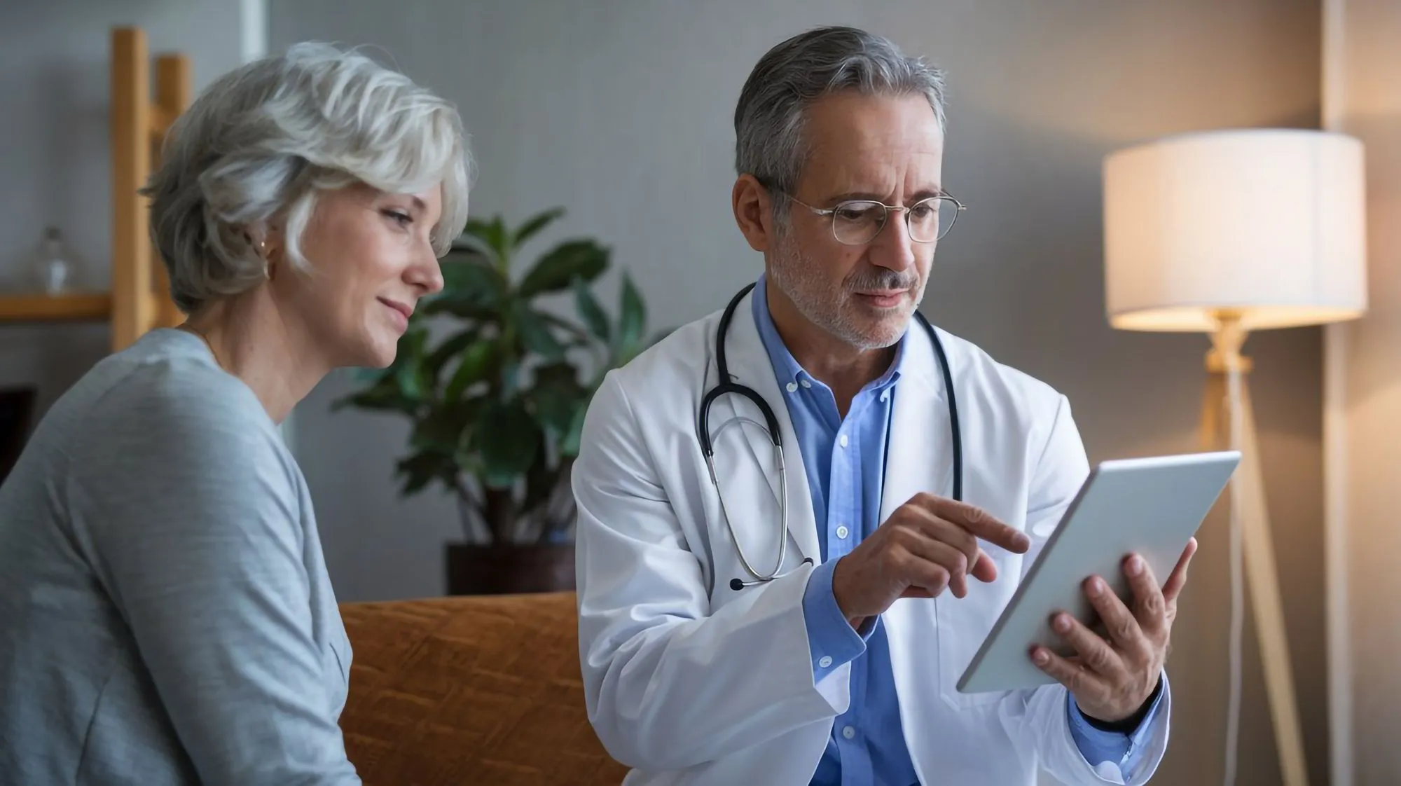 A doctor reviews patient data on a tablet with an older woman, showcasing modern healthcare technology in action.