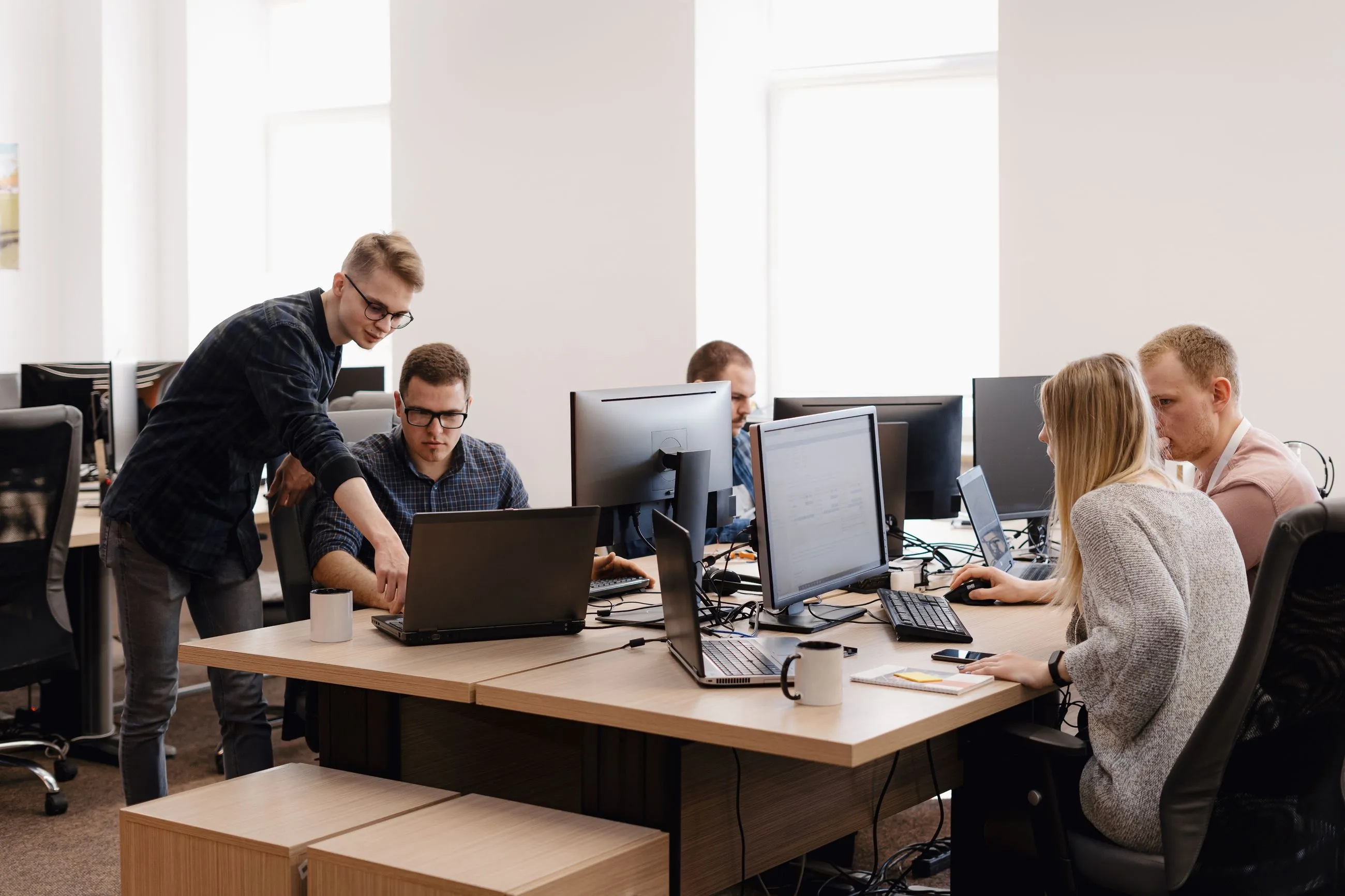 A diverse group of professionals collaborating on computers in an office, focused on optimizing nonprofit operations with Salesforce.