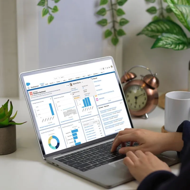A person using a laptop displaying a dashboard for a custom Salesforce CRM, showcasing automated workflows and partner matching.