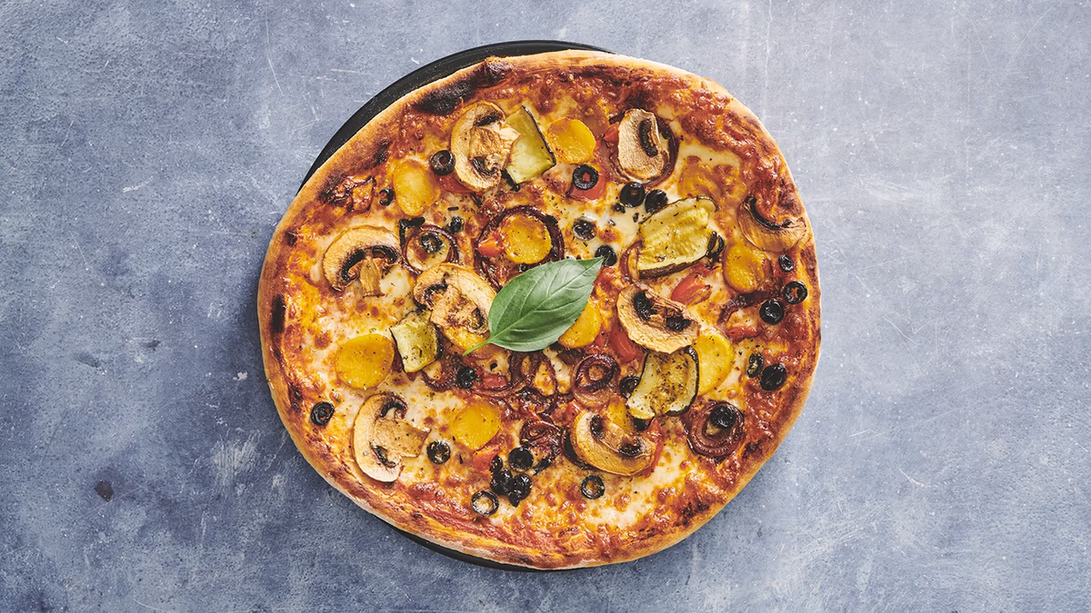 Autentisk italiensk stenovnspizza Vegetariana (V) Tomatsauce, mozzarella, oregano, tynde kartoffelskiver, grillet squash, grillet peberfrugt, rødløg, champignon og frisk basilikum friskbagt på Amagerbro
