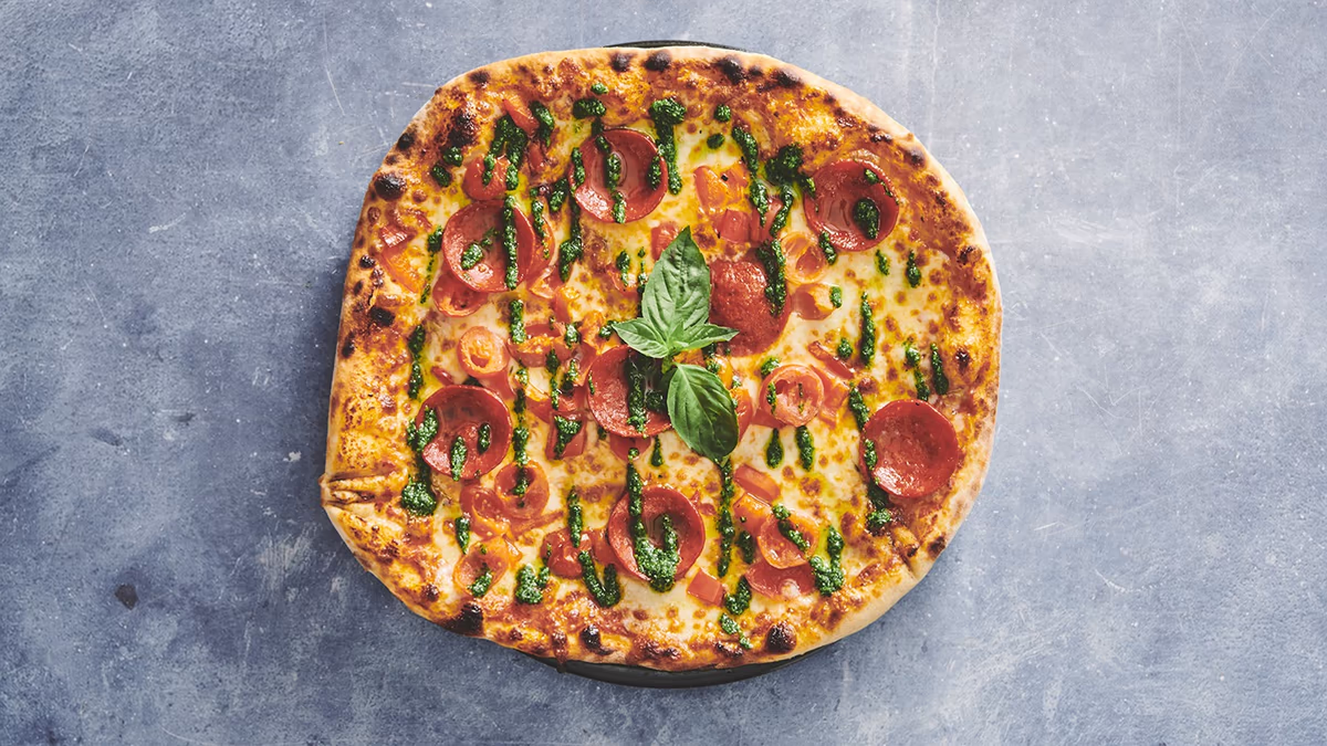 Autentisk italiensk stenovnspizza Esmeralda Speciale Tomatsauce, mozzarella, oregano, pepperoni, cherry tomater, paprika, pesto og frisk basilikum friskbagt på Amagerbro