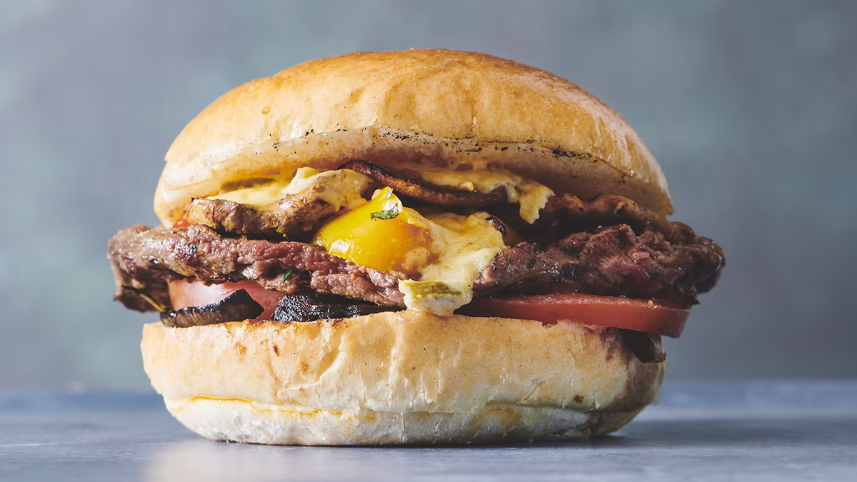 Autentisk italiensk stenovnspizza Steak burger Saftig grillet oksemørbrad med tomat, rødløg, pandestegte champignoner, grillet peberfrugt og cheddarostsauce.