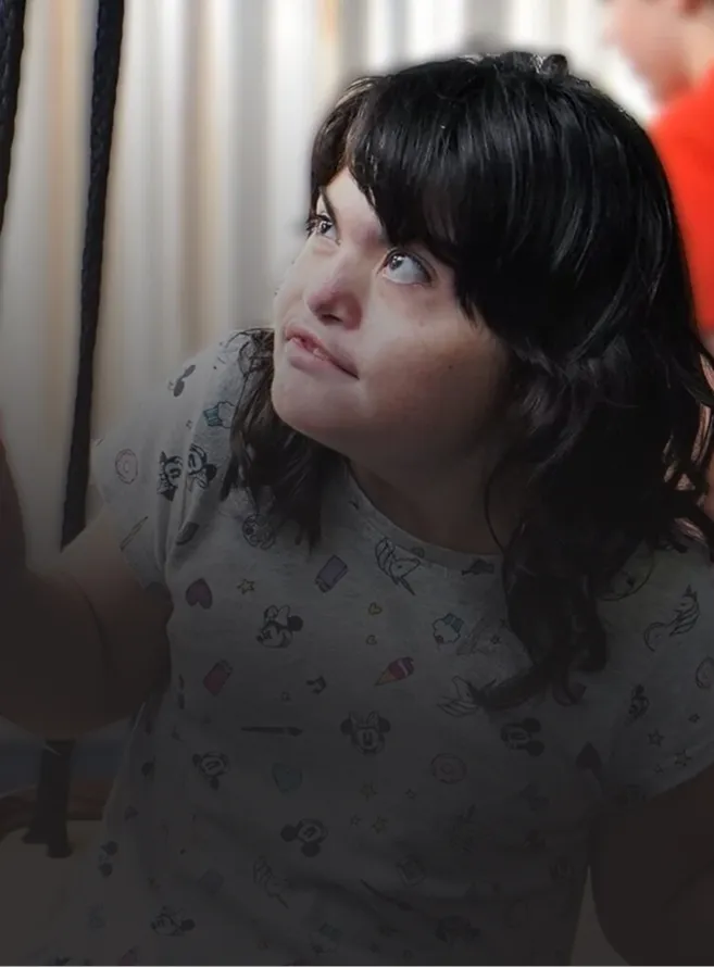 Young woman with dark hair looking upward, wearing a light-colored shirt with small cartoon patterns.