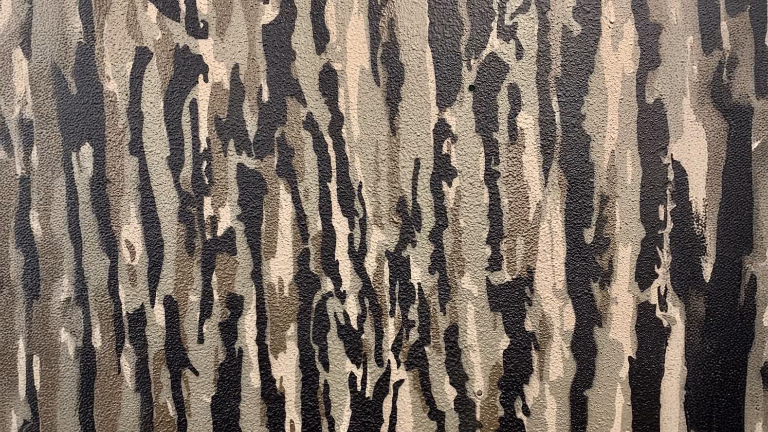 Textured surface painted with vertical camouflage patterns in shades of brown, beige, and black.