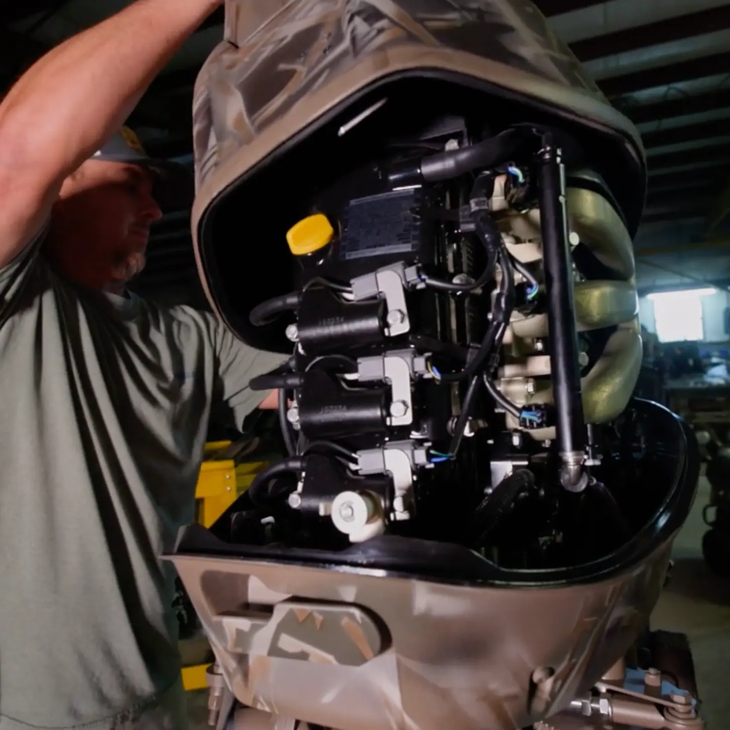 Mechanic lifting the cover of an outboard boat motor showing its engine components.