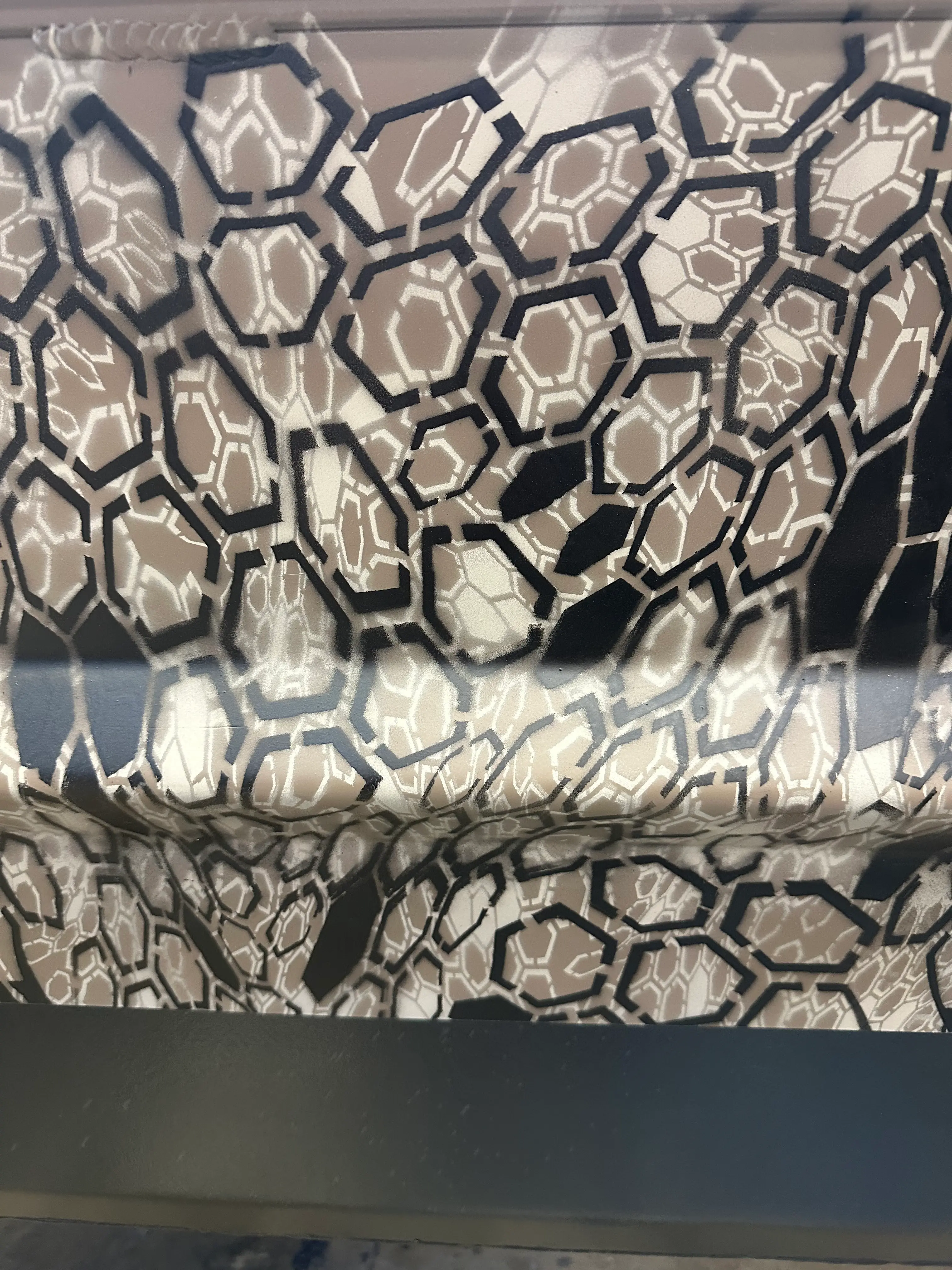 Fabric with hexagonal camouflage pattern in shades of beige, black, and white.