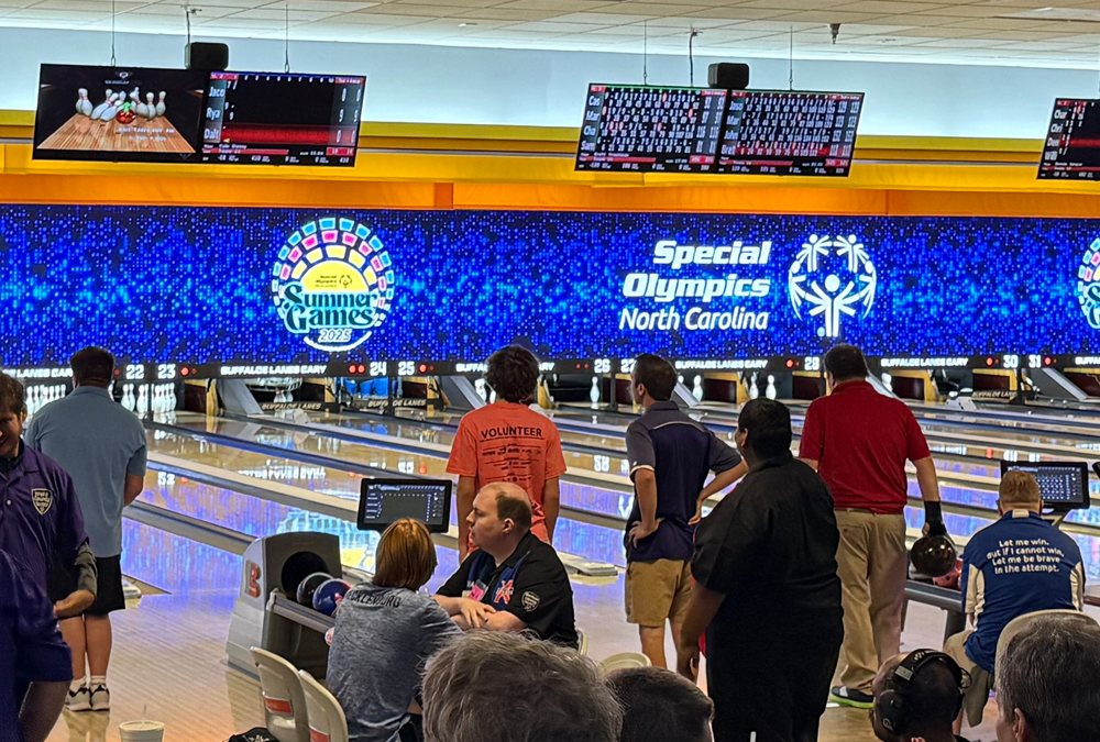 People bowling in an alley with a Special Olympics North Carolina Summer Games 2025 banner in the background.