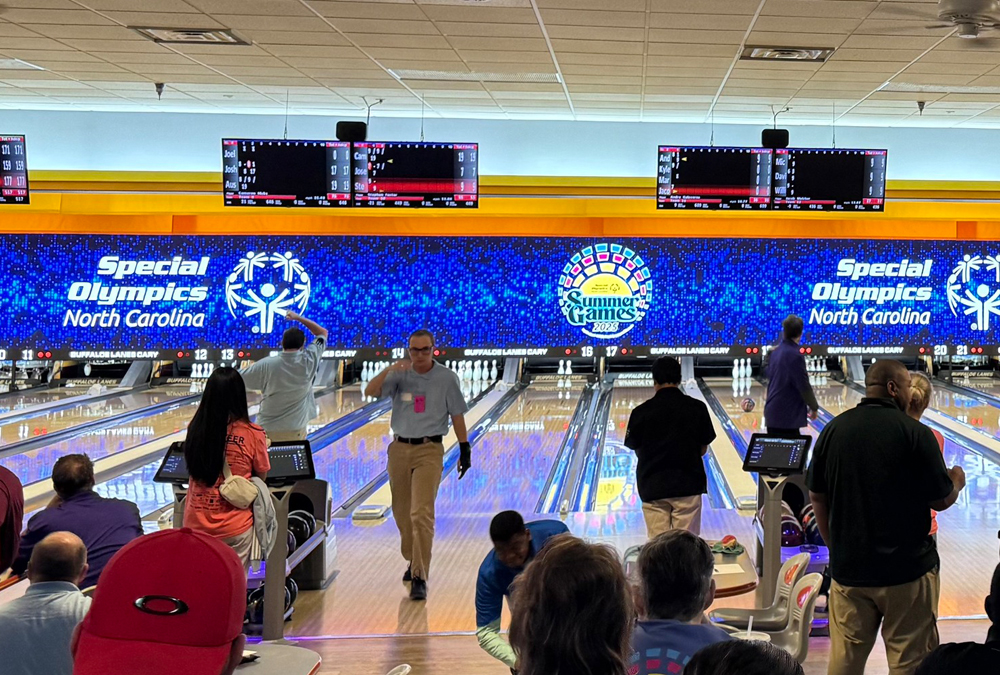 People bowling at Special Olympics North Carolina Summer Games 2023 in a brightly lit bowling alley.