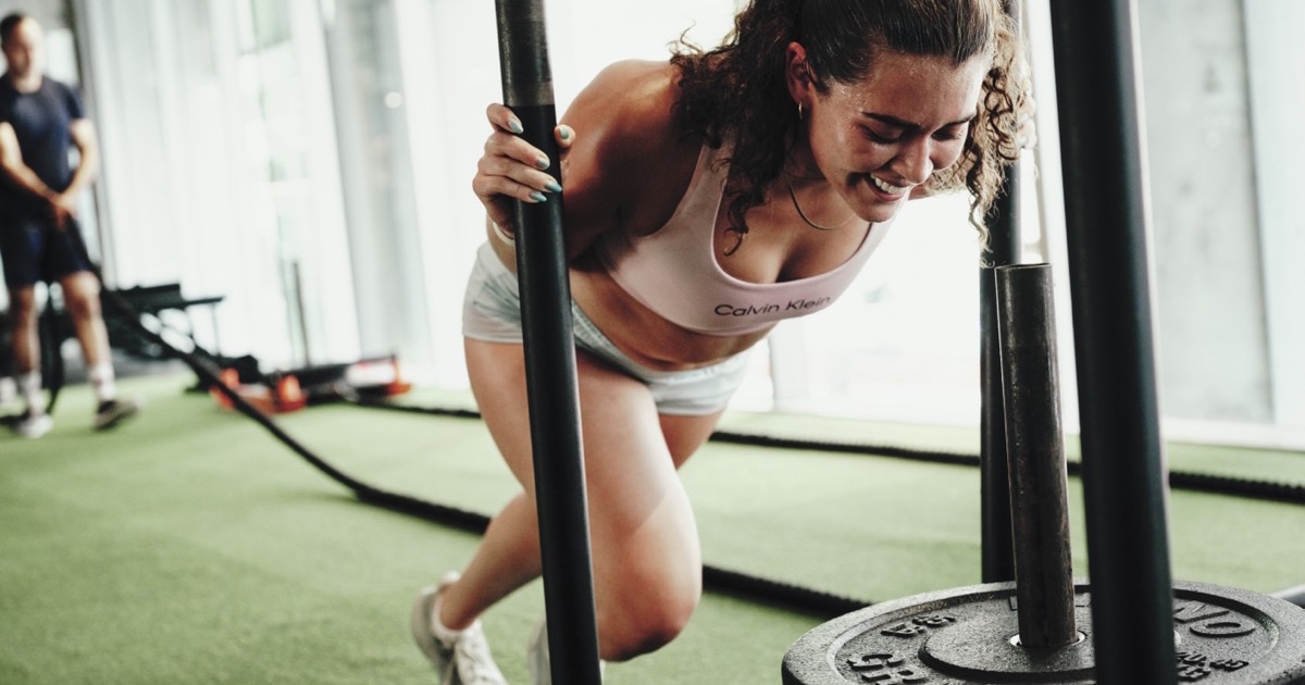 A member pulling a weighted sled with a rope during HYROX training