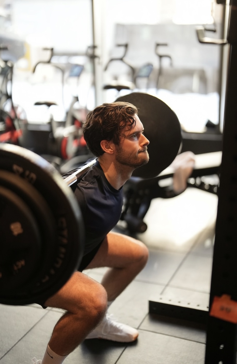 A member lowering into a barbell back squat at Fit Factory
