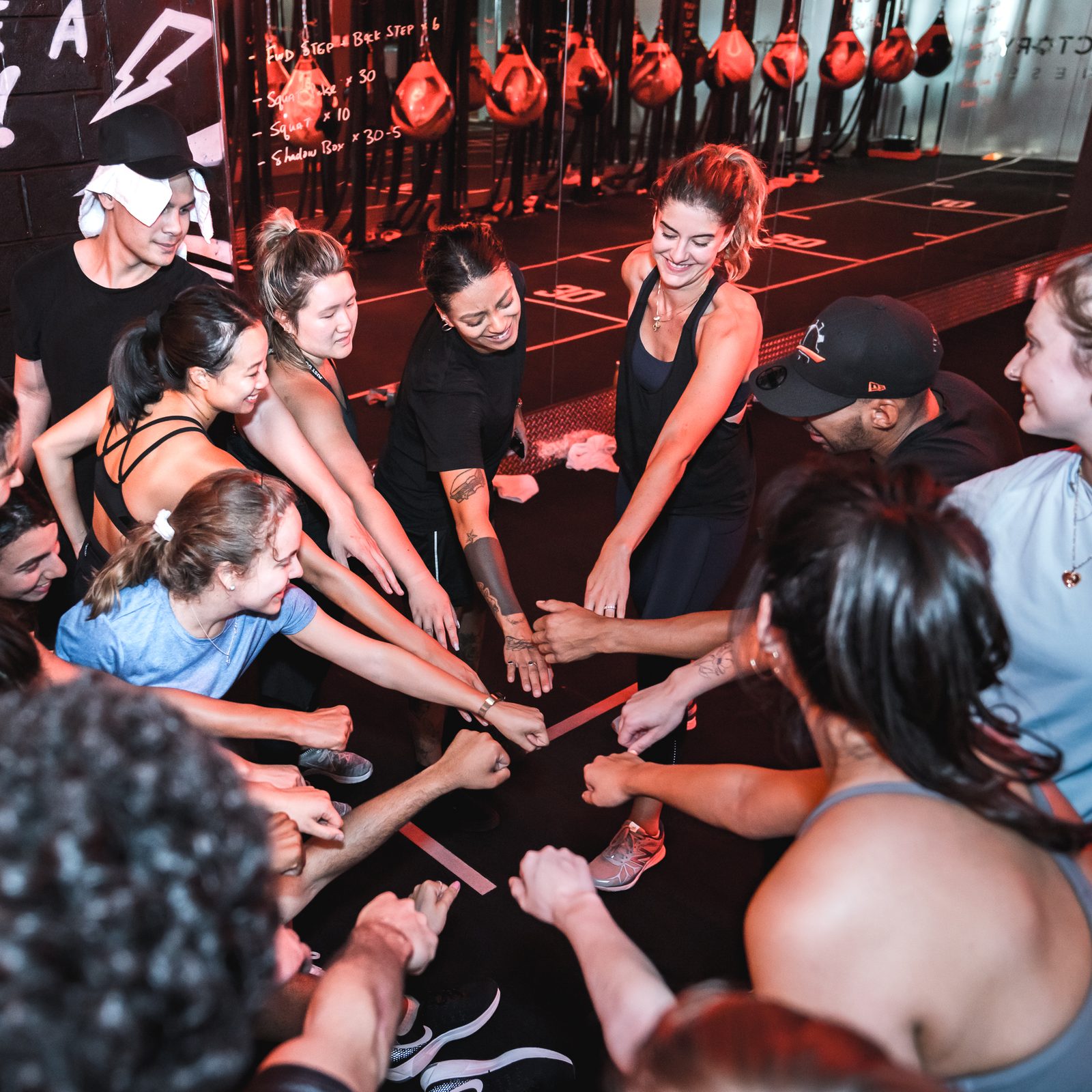 A corporate team and Fit Factory coaches bring their fists together in a huddle after a session in the Downtown boxing room