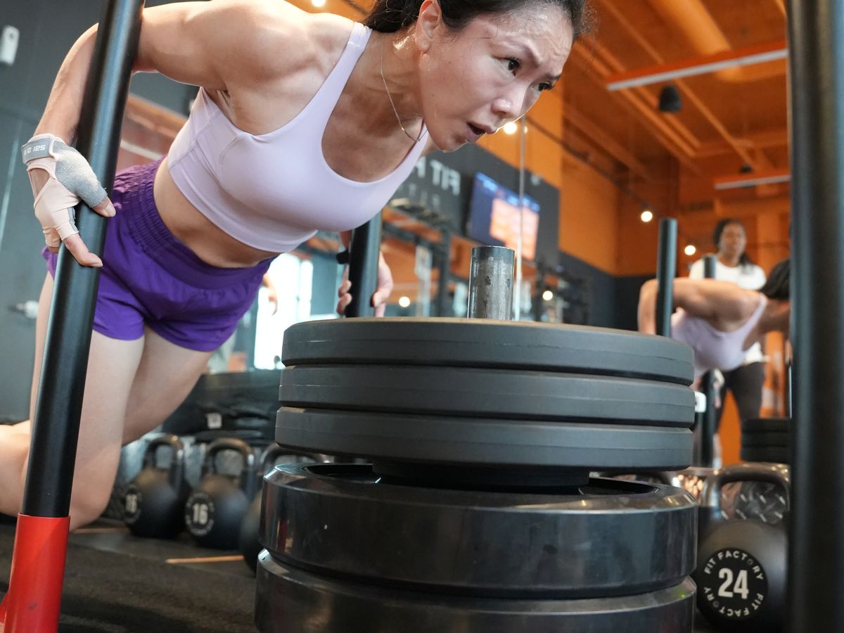 A member pushes a weighted sled under the Fit Factory sign at Midtown