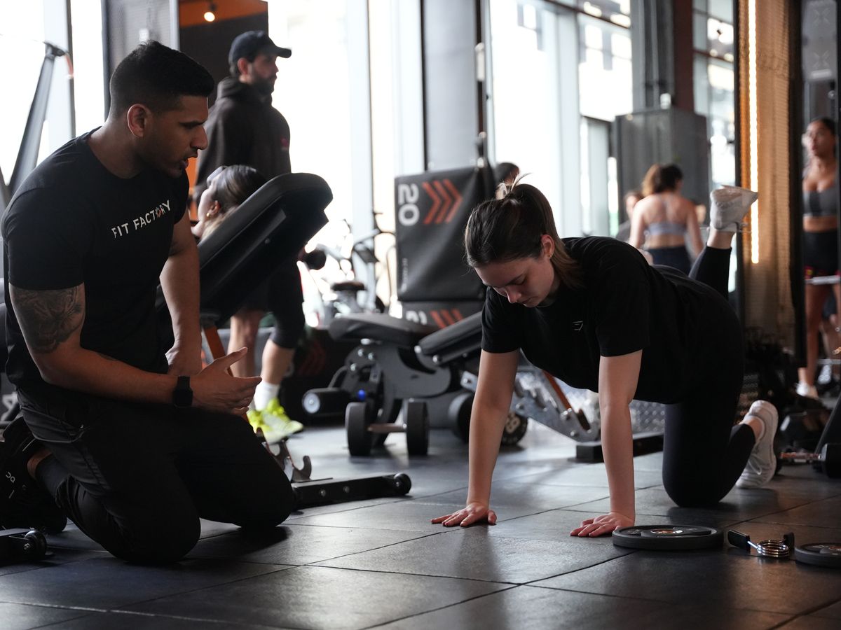 A coach cues a member through floor work at the end of a class at Fit Factory Midtown